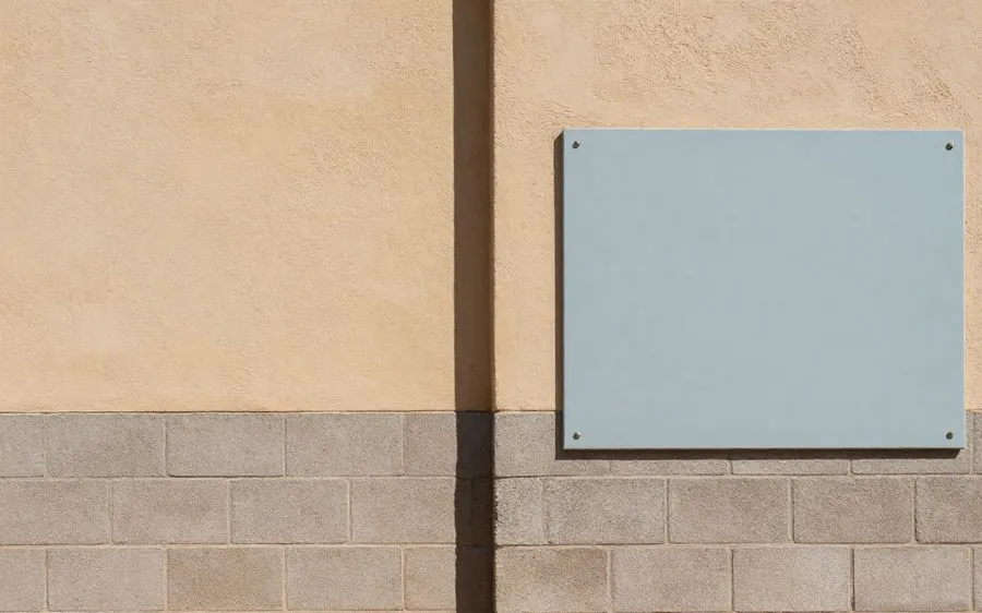 A block wall where a stuccoed and painted section meets bare gray block